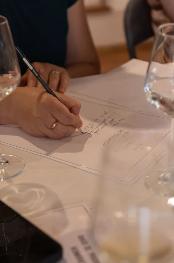 A participant taking handwritten notes on the workshop guide with a pencil