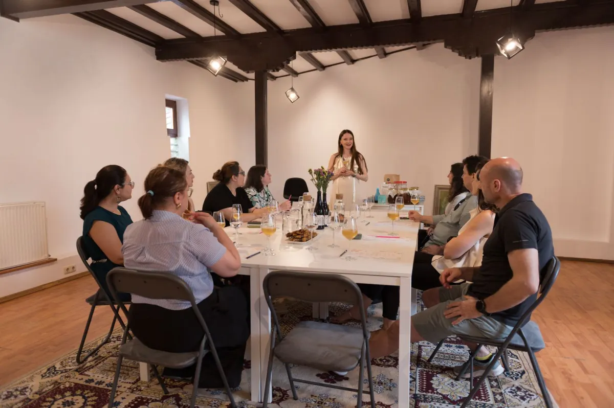 Participants seated around a long white table at the Craft Kombucha Workshop, listening to Ioana at Common House, Bucharest